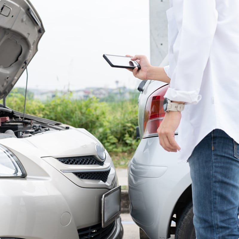 Constat d'accident : déclarer un sinistre par smartphone Conducteur prenant des photos d'un accrochage entre deux voitures pour un constat d'accident avec son smartphone.