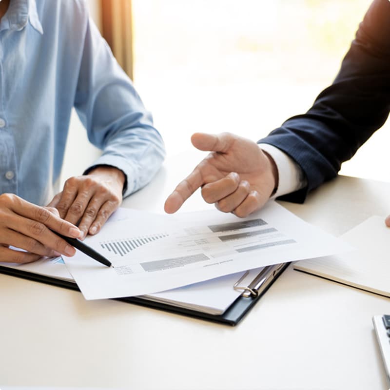 Analyse de Rapport Financier : Réunion Stratégique Deux professionnels analysent un rapport financier avec graphiques lors d'une réunion d'affaires au bureau.