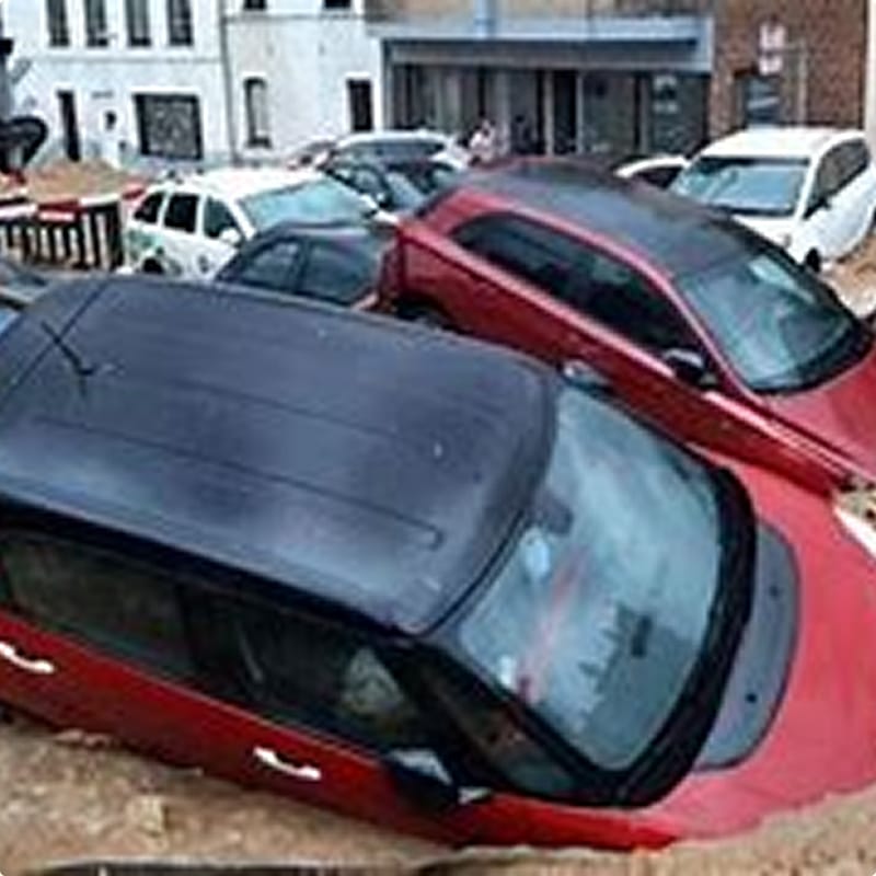 Inondations urbaines : Voitures piégées dans la boue Plusieurs véhicules submergés par la boue et les inondations dans une rue urbaine, voiture rouge au premier plan.